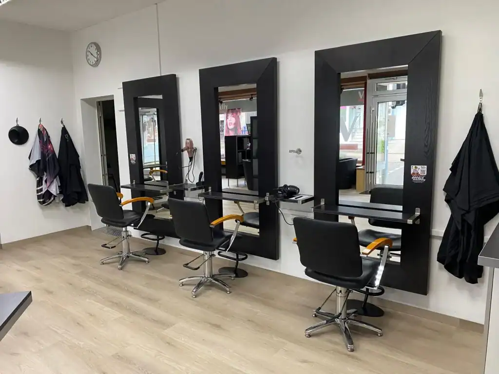 A salon with chairs and mirrors in it.